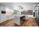 Modern kitchen with white cabinets, stainless appliances, large island, and hardwood floors at 4766 S Fillmore Ct, Cherry Hills Village, CO 80113