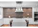 A modern kitchen with stainless hood vent, oversized island and hardwood flooring at 4766 S Fillmore Ct, Cherry Hills Village, CO 80113