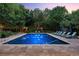 A serene pool setting is beautifully framed by trees, creating a private outdoor oasis with deck chairs around the illuminated pool at 4766 S Fillmore Ct, Cherry Hills Village, CO 80113