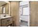 Stylish bathroom featuring wood cabinetry, mirror, and wood plank walls leading to another toilet area at 62681 E Hampden Pl, Byers, CO 80103
