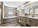 Stylish bathroom features double sinks, wood cabinetry, and a separate tub and shower at 62681 E Hampden Pl, Byers, CO 80103