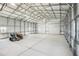 Spacious interior view of detached garage with rolling doors and room for storage at 62681 E Hampden Pl, Byers, CO 80103