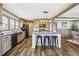 Bright kitchen with wooden cabinets, black appliances, large center island and modern light fixture at 62681 E Hampden Pl, Byers, CO 80103