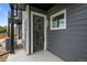 Modern front door with glass panes, complemented by the gray exterior and a glimpse of the interior stairs at 2736 W 68Th Ave, Denver, CO 80221