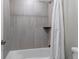 Tiled bathtub and shower with a shower curtain and a built in shelf for storage at 8255 S Vandriver Way, Aurora, CO 80016