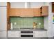 Close-up of modern kitchen details including a gas range, wood cabinets, and green backsplash at 1718 W 33Rd Ave, Denver, CO 80211