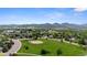 Wide aerial shot capturing a baseball field and a residential area with tree coverage and mountain backdrop at 12277 W Chenango Dr, Morrison, CO 80465
