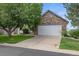 Charming home featuring a stone-accented two-car garage and a well-manicured front yard with mature trees at 12277 W Chenango Dr, Morrison, CO 80465