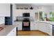 Bright kitchen with white cabinets, black appliances, tile backsplash, and hardwood floors at 12277 W Chenango Dr, Morrison, CO 80465