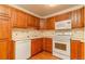 Traditional kitchen featuring wooden cabinetry, laminate countertops, and modern white appliances at 580 S Clinton St # 10D, Denver, CO 80247