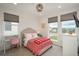 Well-lit bedroom with three large windows, carpet, and a nicely decorated bed with pink pillows and comforter at 5866 Boston Ct, Denver, CO 80238