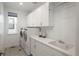 Clean laundry room with white cabinets, counter space, a sink, and a front-load washer and dryer at 5866 Boston Ct, Denver, CO 80238