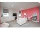 Comfortable living room with a sofa, pink accent wall with desk, and storage cabinets below the window at 5866 Boston Ct, Denver, CO 80238