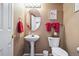 Charming half-bathroom with pedestal sink, toilet, and decorative mirror and towel rack at 9421 Morning Glory Ln, Highlands Ranch, CO 80130