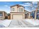 Two-story home featuring a two car garage and brick accents, and snow-covered lawn at 9421 Morning Glory Ln, Highlands Ranch, CO 80130