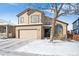 Two-story home boasts a two car garage, neutral exterior, arched window, and snowy yard at 9421 Morning Glory Ln, Highlands Ranch, CO 80130