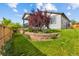 Beautiful backyard featuring a stone retaining wall, lush lawn, mature trees, and well-maintained landscaping at 9628 Albion Ln, Thornton, CO 80229