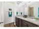 Bathroom with dual sinks, granite countertops, and dark wood cabinets at 9628 Albion Ln, Thornton, CO 80229