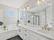 Bright bathroom with a dual vanity, white countertop, stylish light fixtures, bathtub, and glass-enclosed shower at 904 Sundown Way, Erie, CO 80516