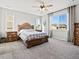 Spacious bedroom with large windows, neutral carpet, a ceiling fan, and a decorative wood-frame bed at 904 Sundown Way, Erie, CO 80516