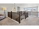 Open hallway with wood railings, neutral carpet, modern light fixture, and views of the living area below at 904 Sundown Way, Erie, CO 80516