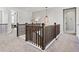 Open hallway with wood railings, neutral carpet, modern light fixture, and views of the living area at 904 Sundown Way, Erie, CO 80516