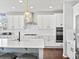 Bright kitchen with white cabinetry, stainless steel range hood, undermount sink, granite countertops and hardwood floors at 904 Sundown Way, Erie, CO 80516