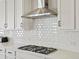 Close up of a kitchen with a stainless steel range hood and white subway tile backsplash at 904 Sundown Way, Erie, CO 80516