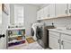 Bright laundry room with modern appliances, white cabinets, shelving, sink, and stylish herringbone flooring at 904 Sundown Way, Erie, CO 80516