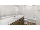 Bathroom with marble-look countertops, wood cabinets, tile surround, and a large mirror at 9303 Biscay St, Commerce City, CO 80022