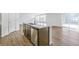 Modern kitchen island featuring a sink, dishwasher, wood cabinets, and views into the light-filled living area at 9303 Biscay St, Commerce City, CO 80022