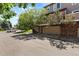 Townhome with a two-car garage, brick accents, and mature trees shading the property at 6825 S Webster St # A, Littleton, CO 80128