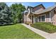 Exterior featuring a manicured front lawn, mature trees and front entrance at 6825 S Webster St # A, Littleton, CO 80128
