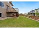 Well-maintained backyard with green lawn, wooden fence, and deck with stairs, ideal for outdoor activities at 9486 Juniper Way, Arvada, CO 80007