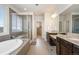 Spacious bathroom featuring a soaking tub, dual vanities with granite countertops, and a glass-enclosed shower at 9486 Juniper Way, Arvada, CO 80007