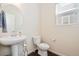 Well-lit powder room with a pedestal sink, round mirror and tiled floors, perfect for guests at 9486 Juniper Way, Arvada, CO 80007