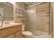 This light-filled bathroom features a shower with glass doors, storage shelves and a wooden vanity at 6544 E Alaska Dr, Denver, CO 80224