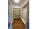 Expansive walk-in closet featuring custom built in shelving and dark wood flooring at 1354 Avgare Way, Erie, CO 80516