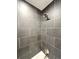 The shower features modern grey tiles with white grout, and updated shower head and fixtures at 2090 S Clinton St, Denver, CO 80231