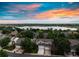 Stunning aerial view showcasing the neighborhood, lake, and vibrant sunset at 849 Canary Ln, Brighton, CO 80601