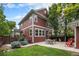 Back exterior view of the home, showing the patio with seating, well-manicured yard and lush greenery at 2908 N Florence St, Denver, CO 80238