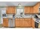 Bright kitchen with natural wood cabinets, stainless steel dishwasher, and a large window at 11285 Iola St, Commerce City, CO 80640