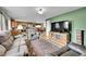 Open-concept living room with a view into the kitchen, showcasing hardwood floors, comfortable seating, and a large TV at 11285 Iola St, Commerce City, CO 80640