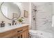 Well-lit bathroom with a wooden vanity, round mirror, and a modern shower with sleek, marble-style tiling at 3713 S Ensenada St, Aurora, CO 80013