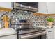 Close up of oven with stainless steel appliances and black and white tile backsplash at 3713 S Ensenada St, Aurora, CO 80013
