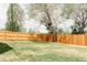 Fenced backyard featuring lush grass and mature trees, providing shade and privacy in a serene setting at 930 S Lowell Blvd, Denver, CO 80219