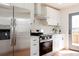Modern kitchen features stainless steel refrigerator, white cabinets, and a glass door at 930 S Lowell Blvd, Denver, CO 80219
