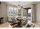 Bright dining room featuring a modern chandelier, a wood table for six, and sliding door access to the outside patio at 11999 S Stroll Ln, Parker, CO 80138