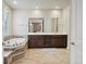 Bright bathroom with tile floors, a soaking tub, double vanity with granite counters, and a large mirror at 11999 S Stroll Ln, Parker, CO 80138