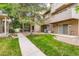 Beautiful backyard area featuring green grass, mature trees, and a concrete walkway at 11155 W 17Th Ave # 103, Lakewood, CO 80215